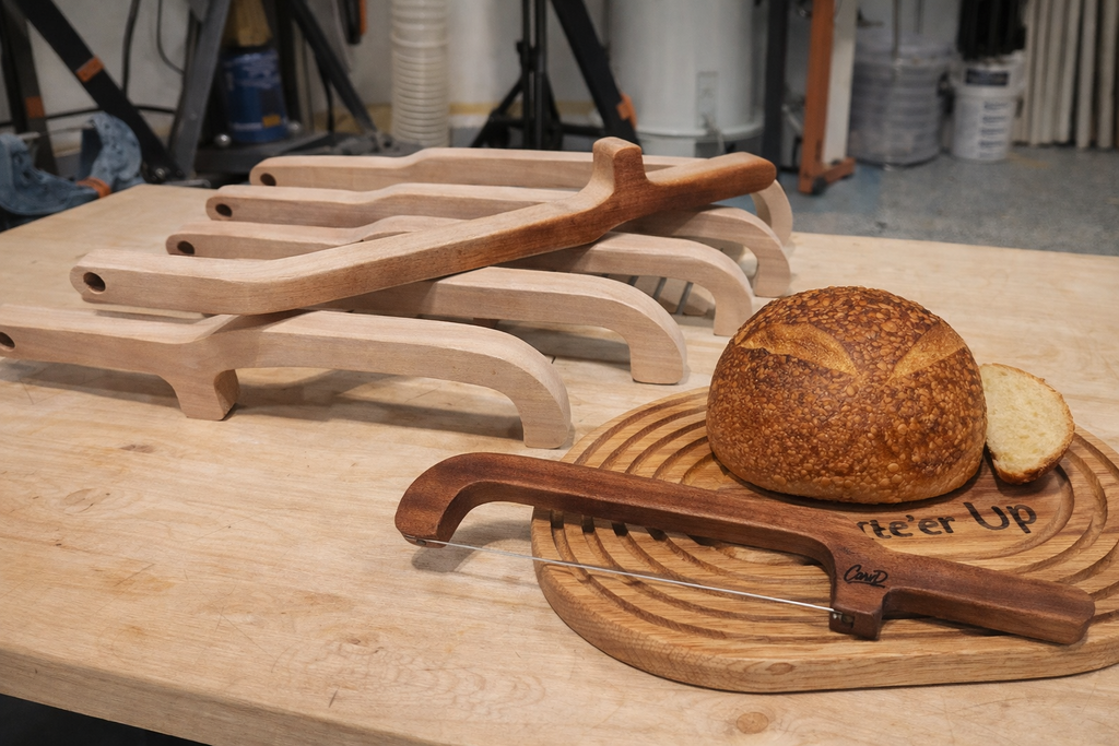 Bread board and knife sets on a wooden surface with a loaf of bread.